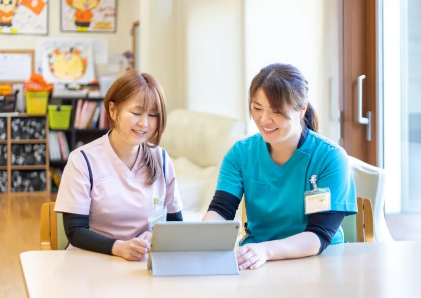 タブレットを見ながら情報共有を行う職員F.R.さんの様子