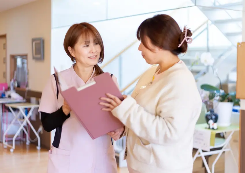 書類を見ながら内容を確認する職員F.R.さんと他職員さんの様子