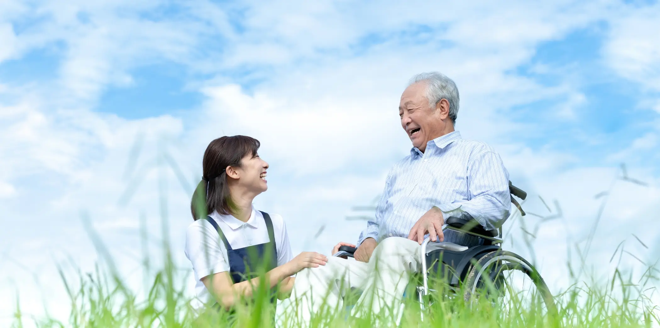 車椅子を利用する高齢者と笑顔で会話する介護スタッフ